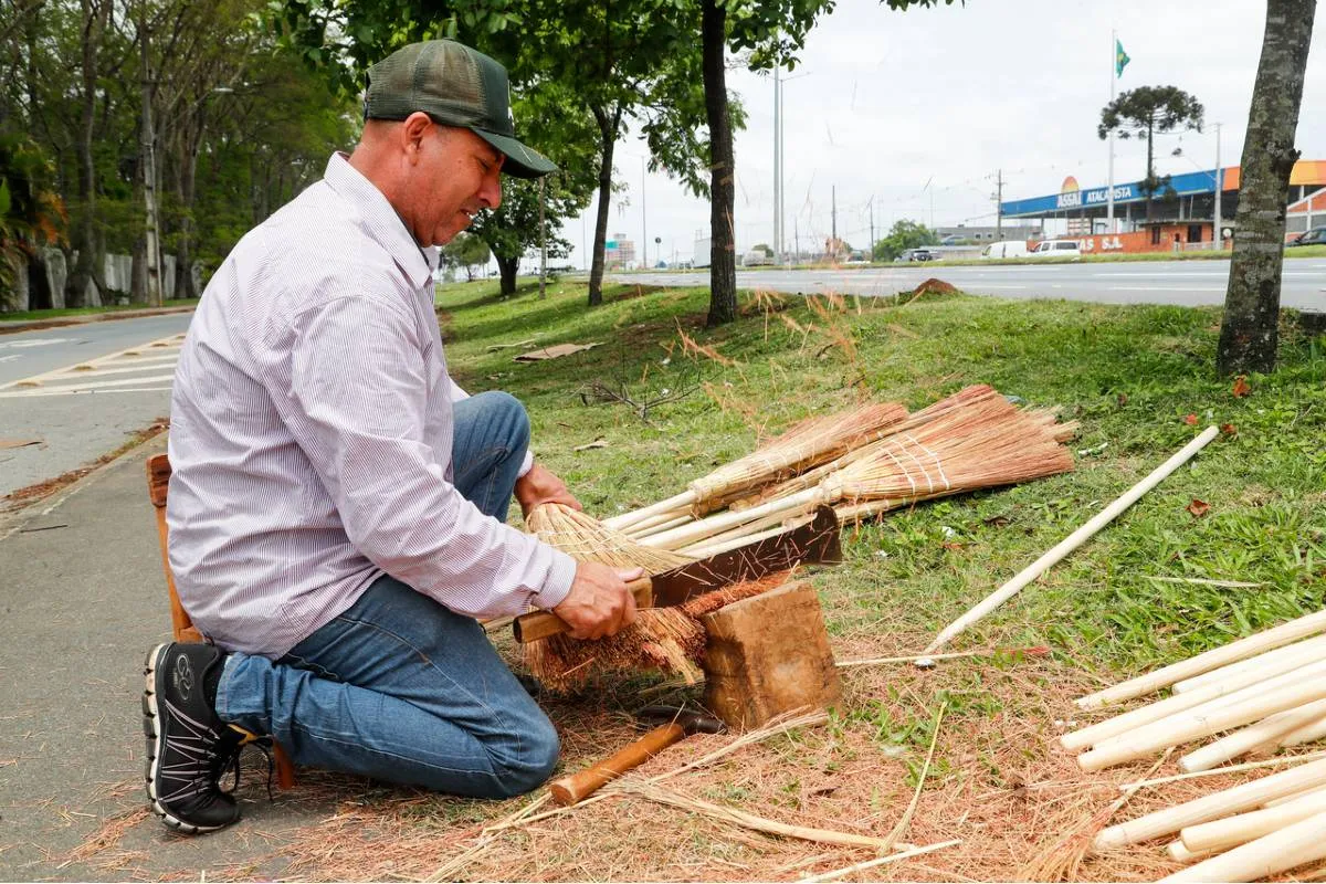 Imagem mostra um homem montando as tradicionais vassouras de palha em Curitiba. 