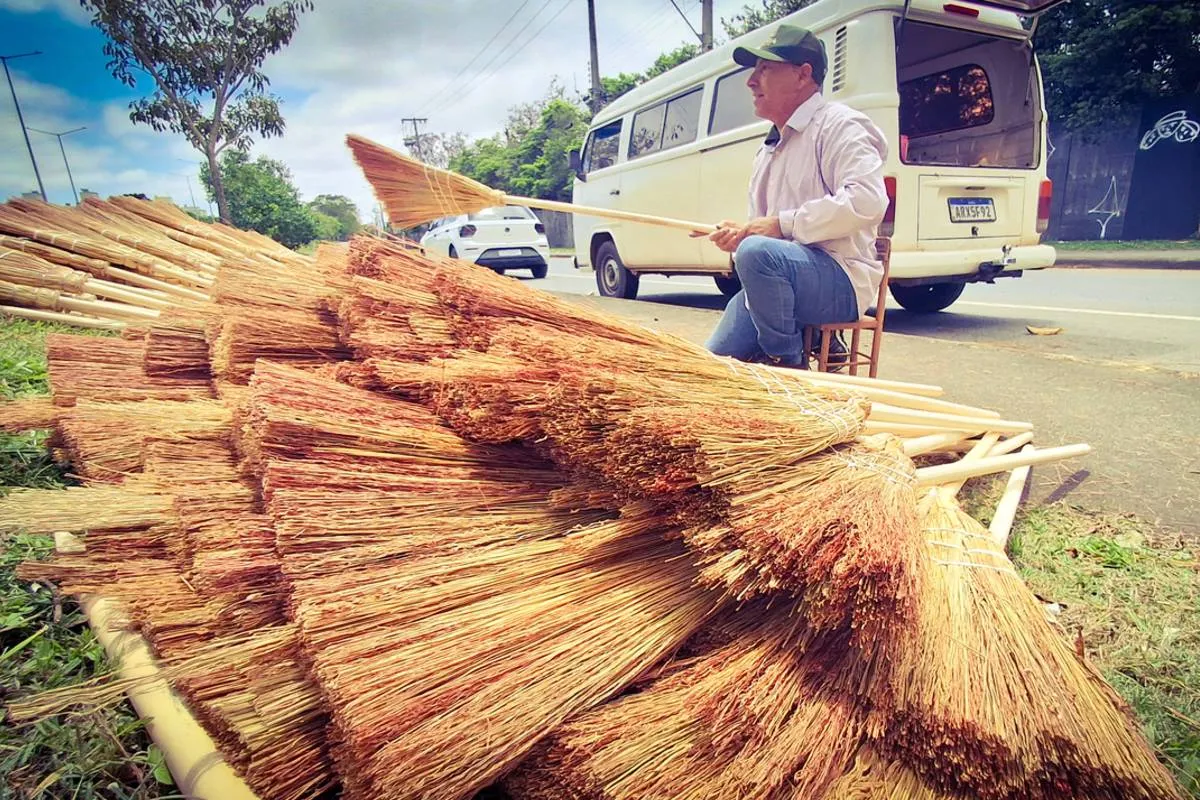 Imagem mostra um homem montando as tradicionais vassouras de palha em Curitiba. 