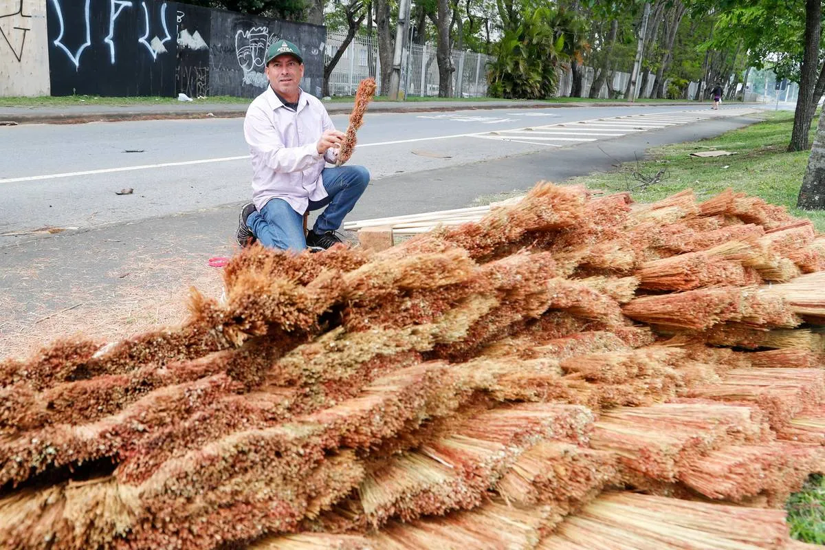 Imagem mostra um homem montando as tradicionais vassouras de palha em Curitiba. 