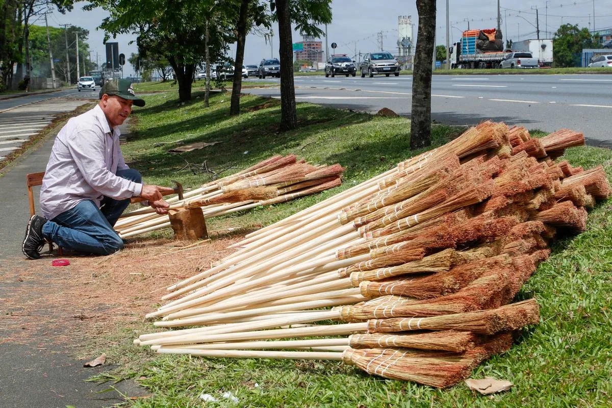 Imagem mostra um homem montando as tradicionais vassouras de palha em Curitiba. 