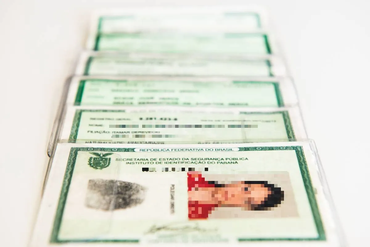 Imagem mostra uma fila com RGs antigos.