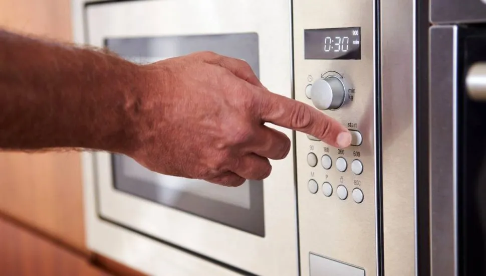 Imagem mostra um forno microondas prateado.