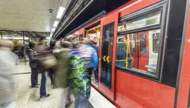 Imagem mostra um metro vermelho com passageiros embarcando