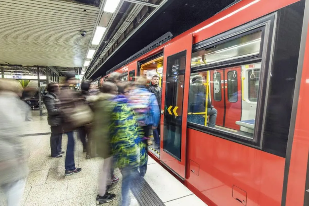 Imagem mostra um metro vermelho com passageiros embarcando