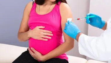 Imagem mostra uma grávida tomando uma vacina.