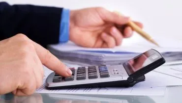 Imagem mostra uma pessoa fazendo contas com uma calculadora.