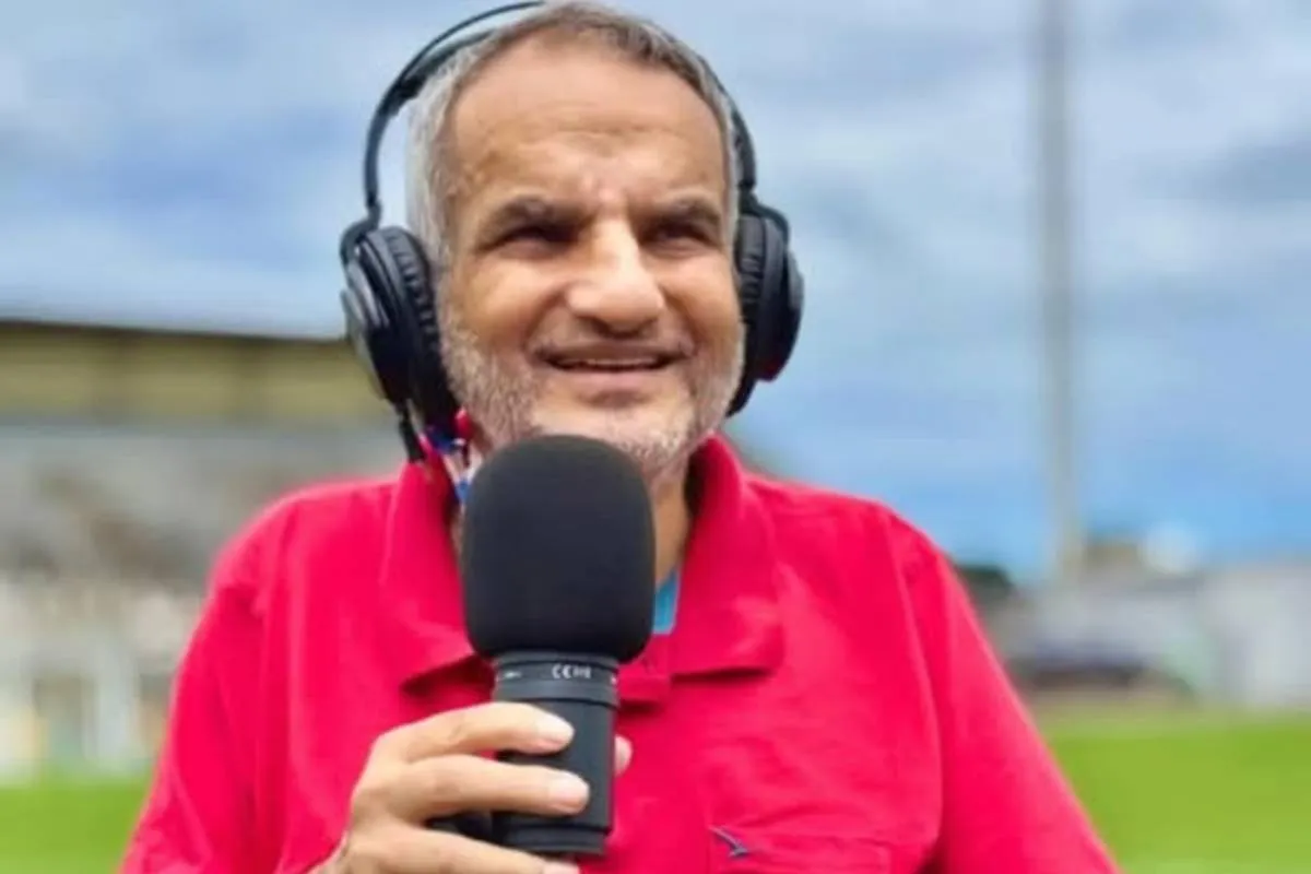 Imagem mostra um radialista com microfone na mão e camisa vermelha.