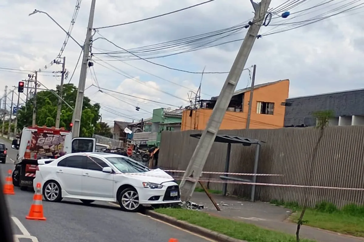 Imagem mostra um carro branco batido contra um poste em Curitiba.
