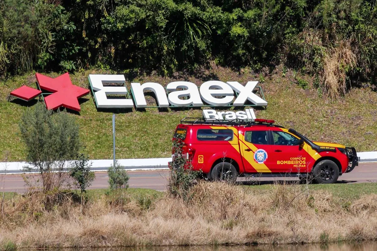 Imagem mostra uma viatura dos Bombeiros passando em frente a uma placa da empresa Enaex Brasil.