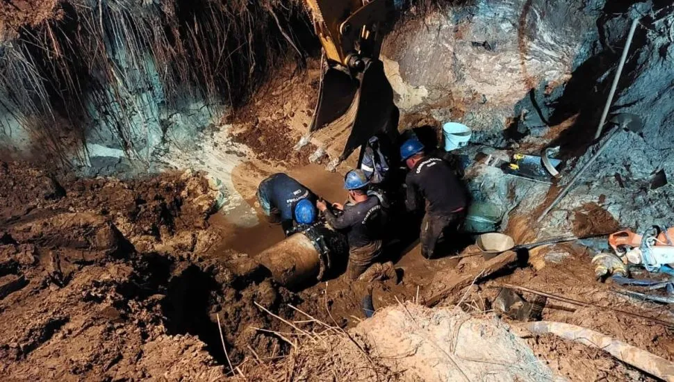 Imagem mostra um operário trabalhando no conserto de uma adutora em um buraco.