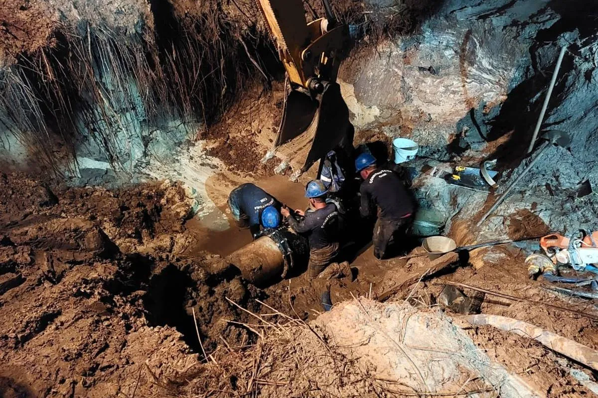 Imagem mostra um operário trabalhando no conserto de uma adutora em um buraco.