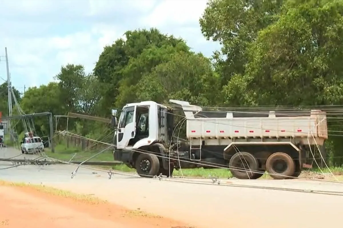 Imagem mostra um caminhão com fios de luz enroscados em uma estrada de chão em Curitiba.