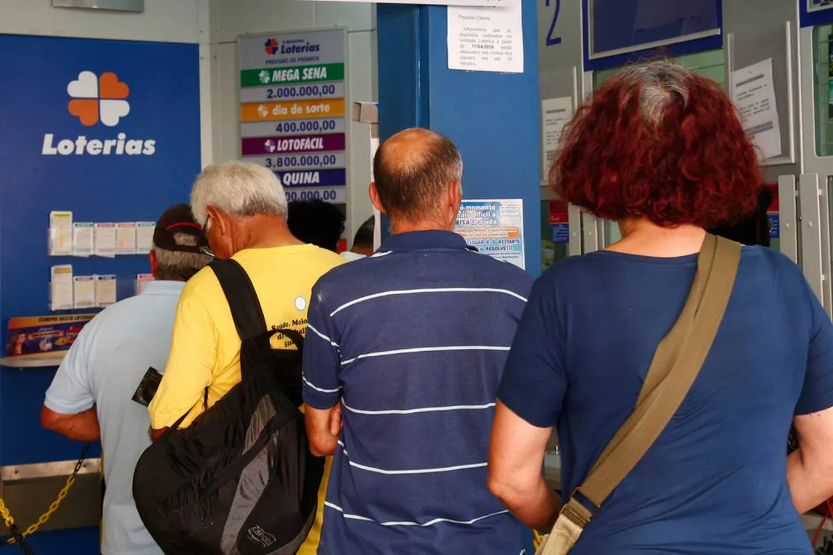 Imagem mostra pessoas na fila de uma lotérica em Curitiba.