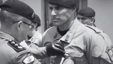 Imagem em preto e brando mostra um policial recebendo uma condecoração.