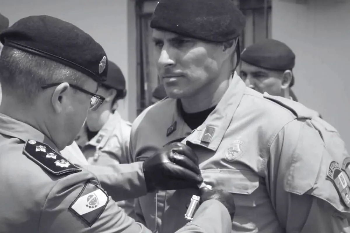 Imagem em preto e brando mostra um policial recebendo uma condecoração.