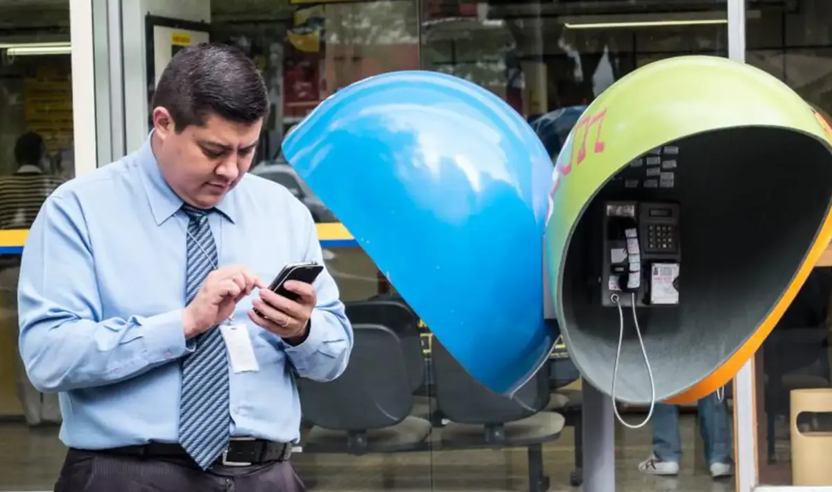 Imagem mostra homem ao lado de dois orelhões