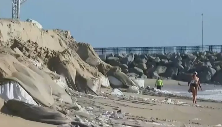 Imagem mostra os sacos para contenção de ressaca se dissolvendo e indo para o mar.