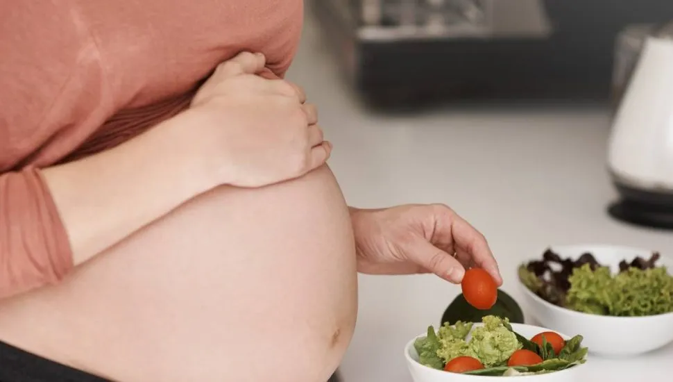 Imagem mostra uma grávida se alimentando.