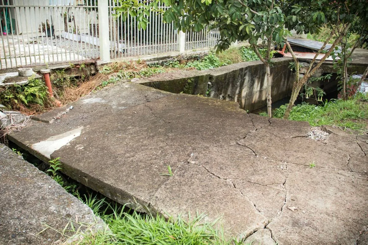 Imagem mostra a Calçada e asfalto cedendo na Rua Joanna Emma Dalpozzo Zardo em Santa Felicidade, às margens do Rio Cascatinha