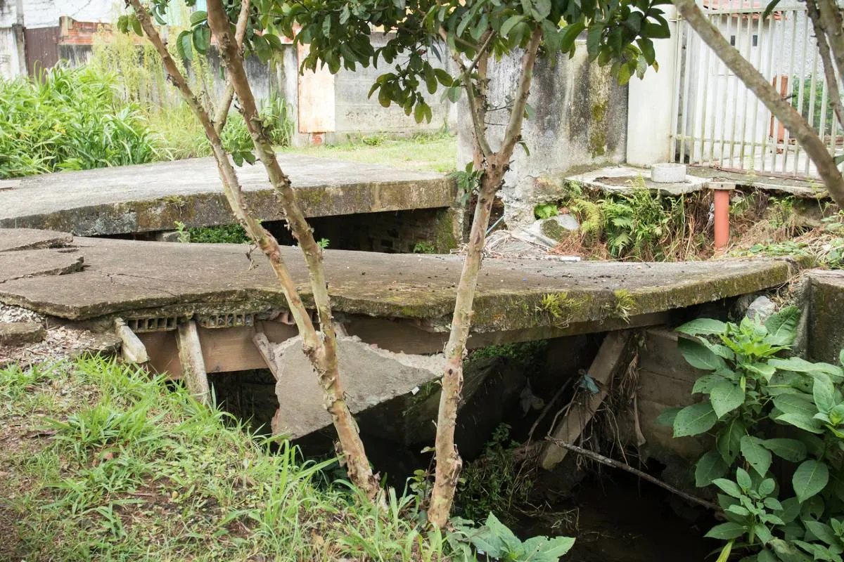 Imagem mostra a Calçada e asfalto cedendo na Rua Joanna Emma Dalpozzo Zardo em Santa Felicidade, às margens do Rio Cascatinha