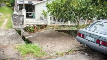 Imagem mostra a Calçada e asfalto cedendo na Rua Joanna Emma Dalpozzo Zardo em Santa Felicidade, às margens do Rio Cascatinha