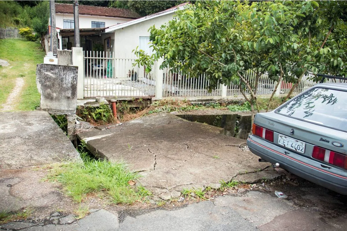 Imagem mostra a Calçada e asfalto cedendo na Rua Joanna Emma Dalpozzo Zardo em Santa Felicidade, às margens do Rio Cascatinha