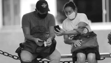 Imagem mostra duas pessoas conversando na época da pandemia de covid-19.