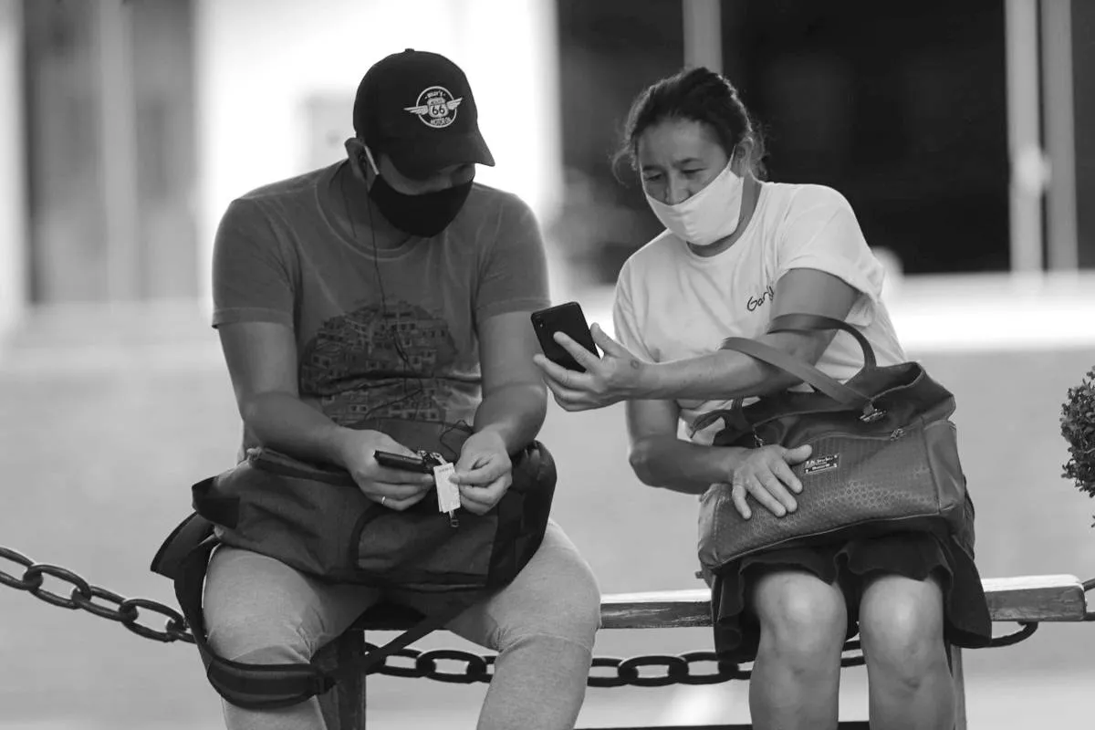 Imagem mostra duas pessoas conversando na época da pandemia de covid-19.