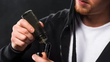 Imagem mostra um rapaz utilizando um VAPE