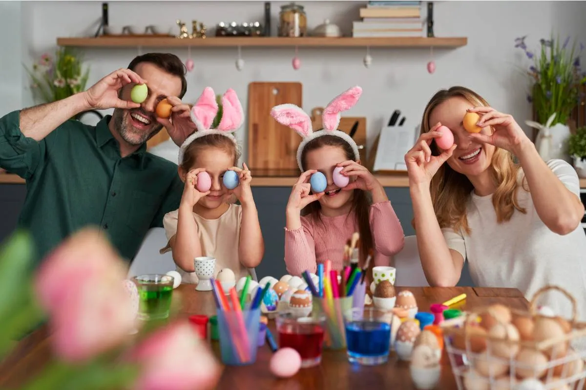 Imagem mostra uma familia brincando com ovos de chocolate na pascoa.