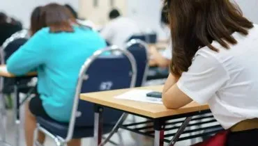Imagem mostra duas mulheres em uma sala de aula com aplicação de prova de concurso público.