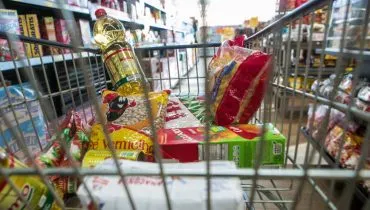 Imagem mostra um carrinho de mercado cheio de produtos.
