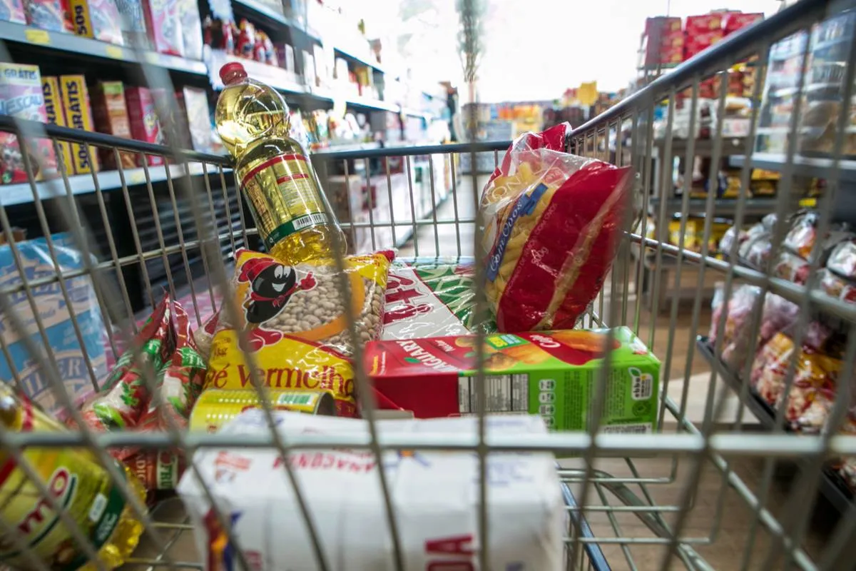 Imagem mostra um carrinho de mercado cheio de produtos.