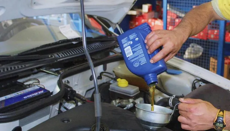 Imagem mostra uma troca de óleo feita em um carro. 