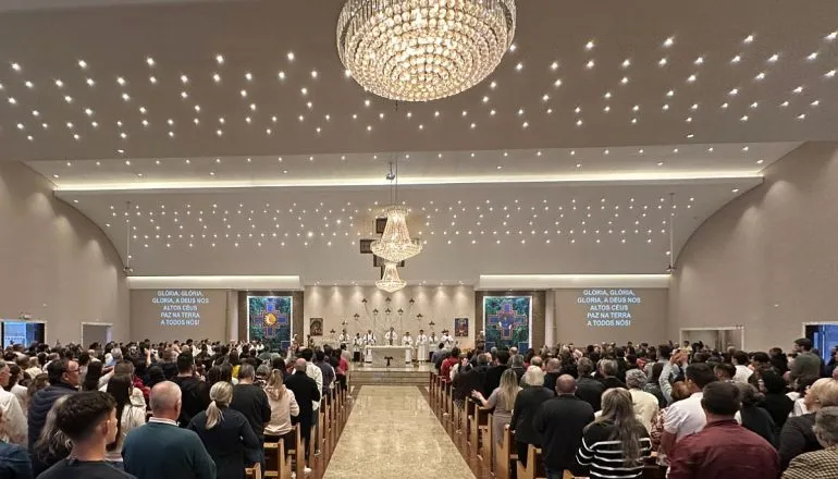 Imagem mostra missa realizada no santuário. Centenas de pessoas ocupam os bancos da igreja
