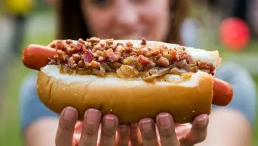 Imagem mostra uma mulher segurando um cachorro quente com uma vina, que pode se tornar calendário oficial de Curitiba.