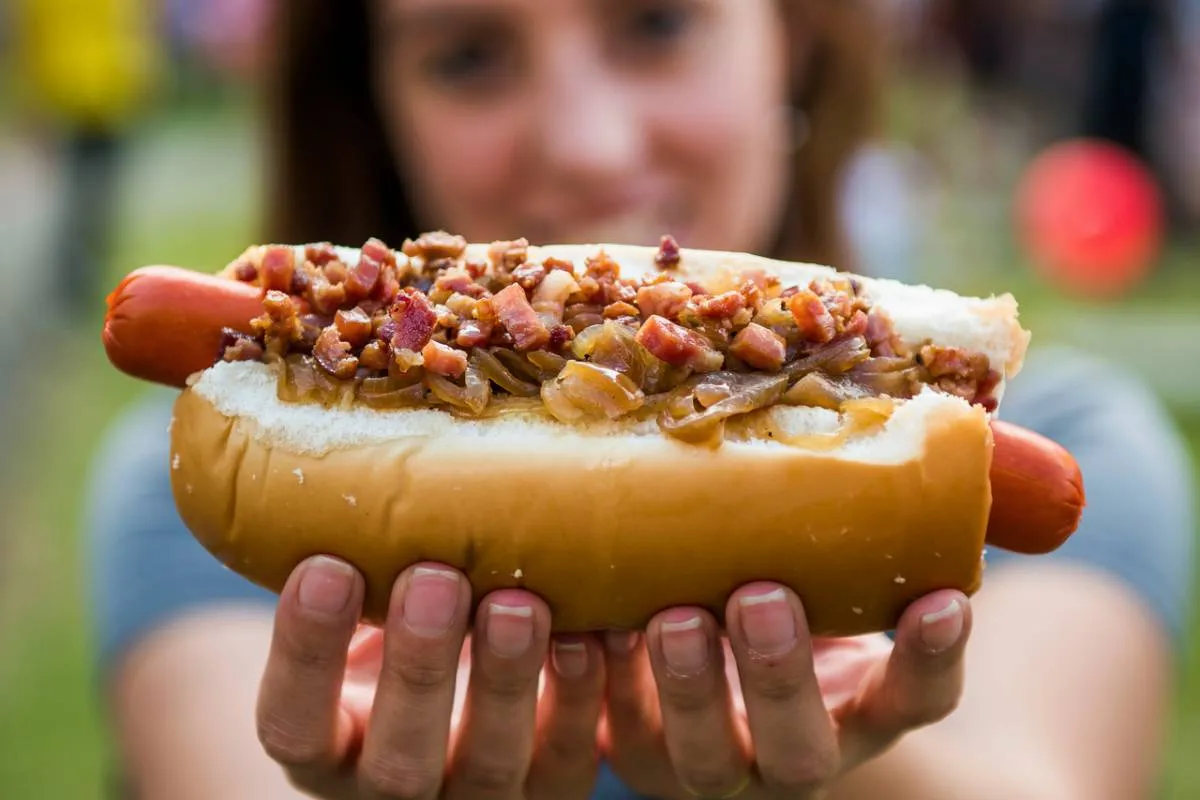 Imagem mostra uma mulher segurando um cachorro quente com uma vina, que pode se tornar calendário oficial de Curitiba.