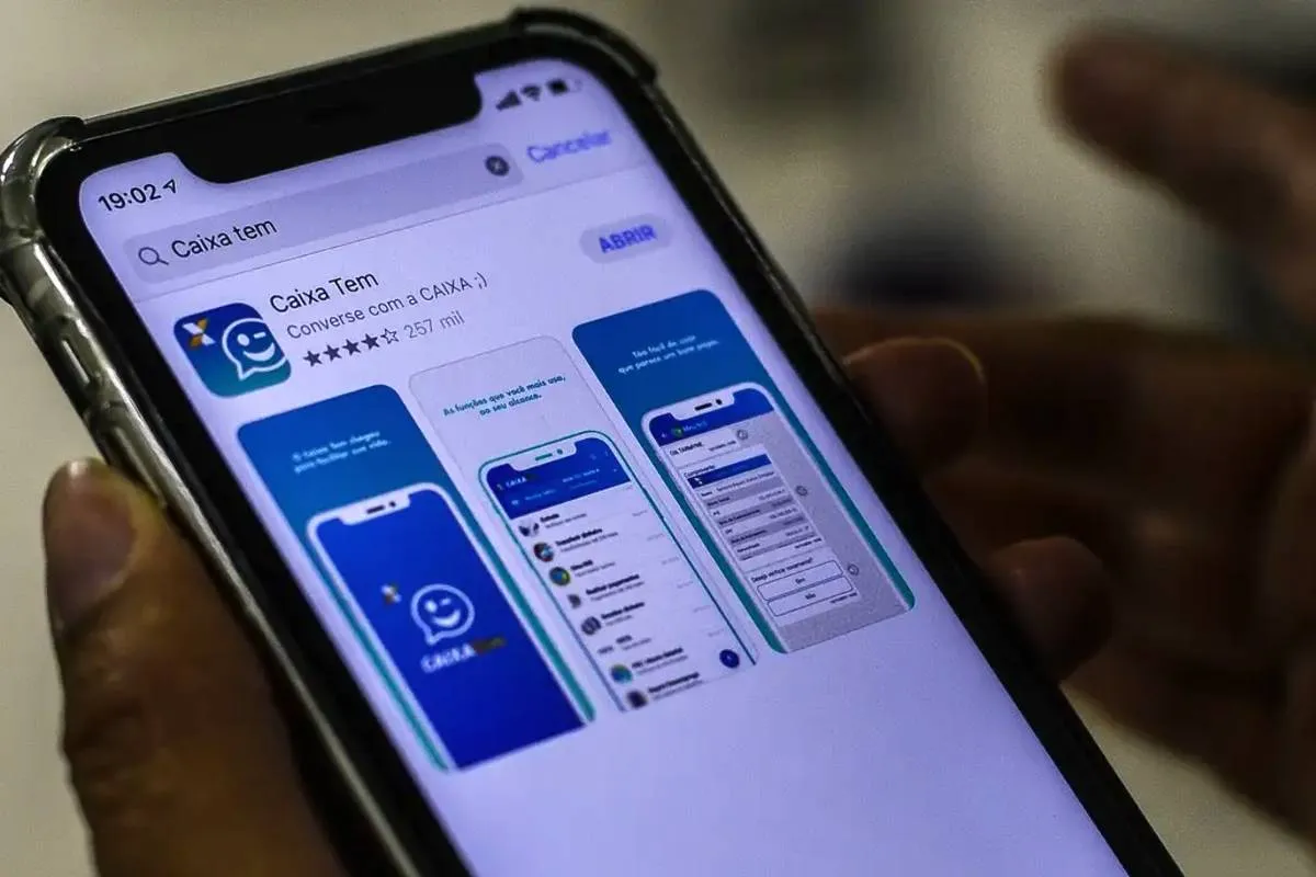 Imagem mostra uma pessoa segurando um celular aberto na página de instalação ao app Caixa Tem.