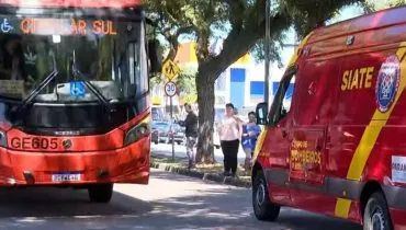 Imagem mostra um ônibus vermelho ao lado de uma viatura dos bombeiros