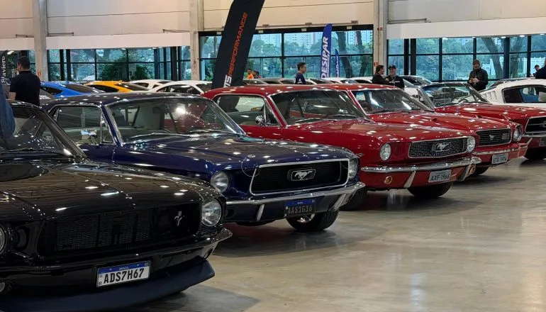 Imagem mostra veículos modelo Mustang estacionados  em uma exposição.