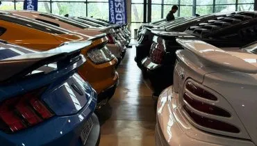 Imagem mostra veículos modelo Mustang estacionados em uma exposição.