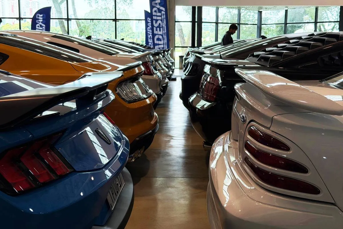 Imagem mostra veículos modelo Mustang estacionados em uma exposição.