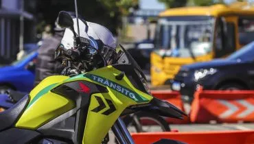Imagem mostra uma moto da Secretaria de Trânsito de Curitiba. A moto é verde e tem o escrito "Trânsito" em sua carenagem.