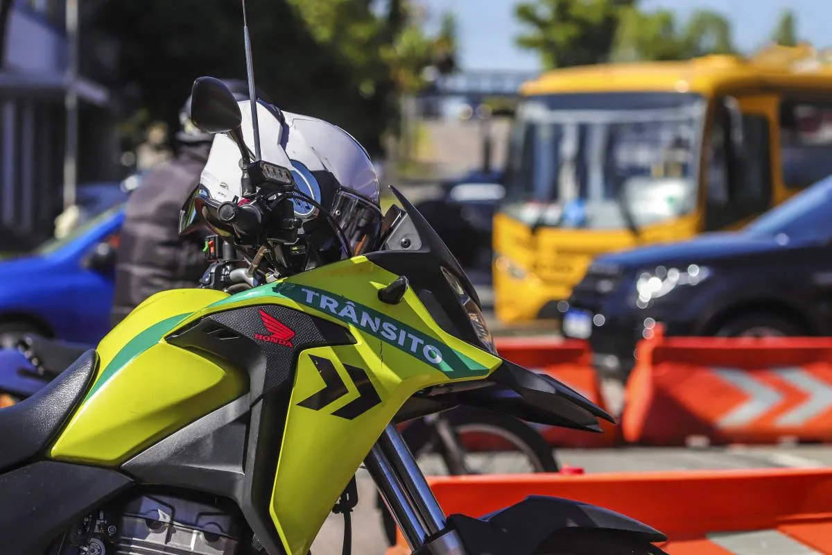 Imagem mostra uma moto da Secretaria de Trânsito de Curitiba. A moto é verde e tem o escrito "Trânsito" em sua carenagem.