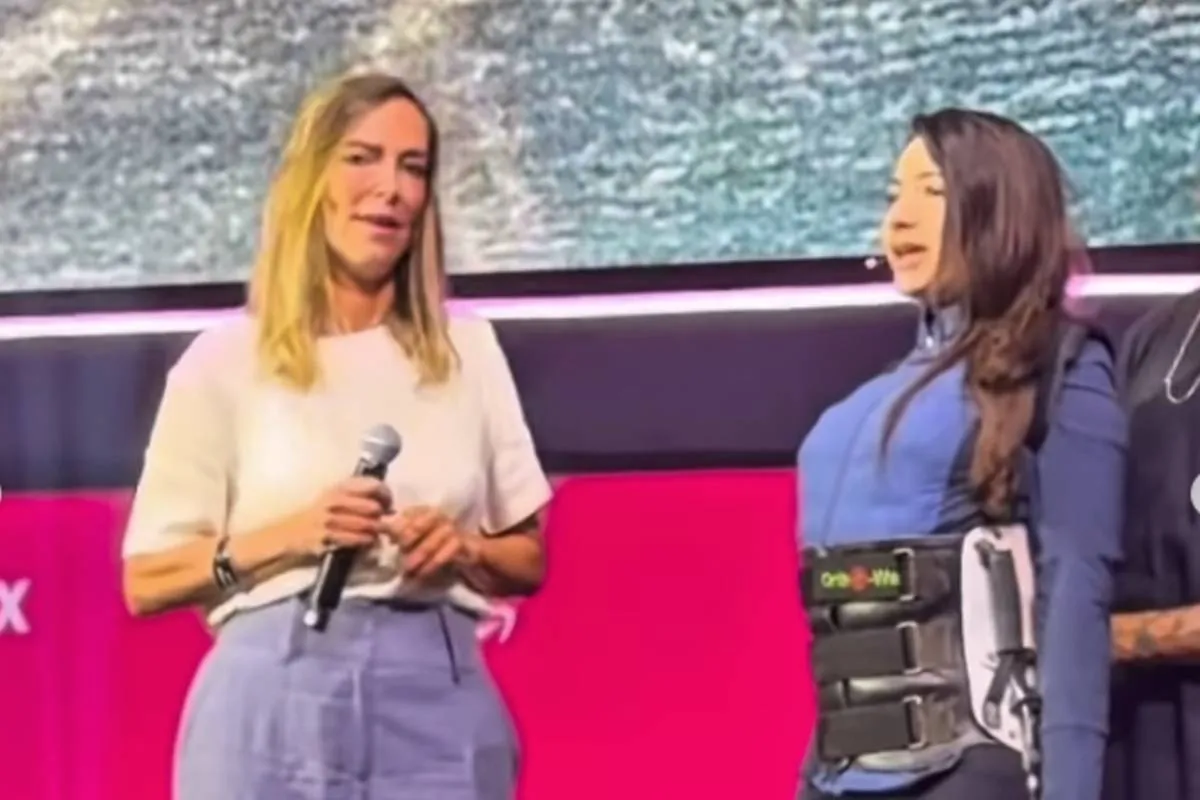 Imagem mostra Lais Souza em pé, com a ajuda de uma ortese, ao lado da Dra Tatiana Sampaio.