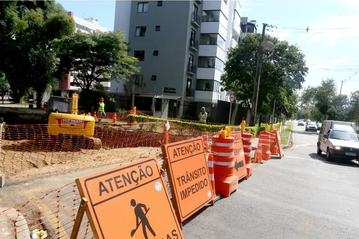 Imagem mostra uma rua com grande bloqueio e placas de sinalização.