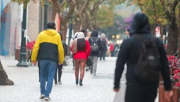 Imagem mostra pessoas com blusas e casacos enfrentando um dia de bastante frio em Curitiba.