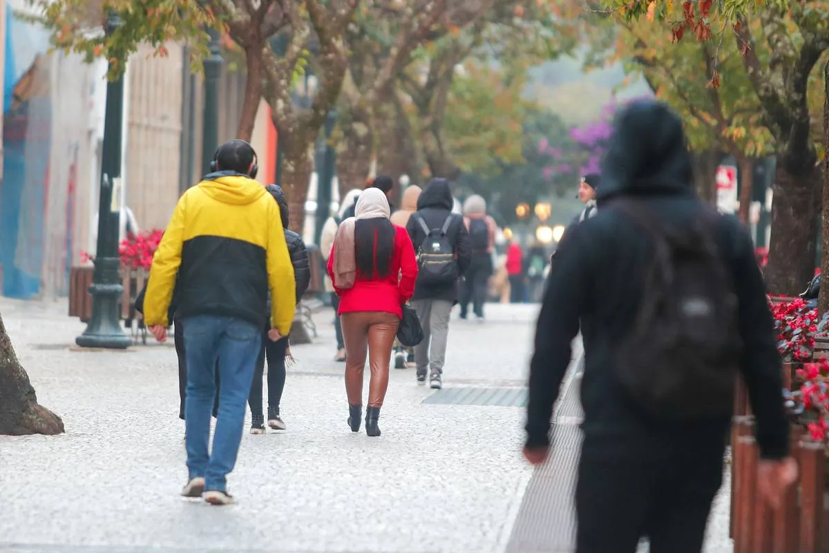 Imagem mostra pessoas com blusas e casacos enfrentando um dia de bastante frio em Curitiba.