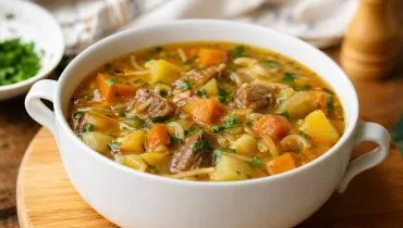 Imagem mostra uma saborosa sopa de legumes em um bowl branco.