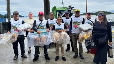 Imagem mostra um grupo de ambulantes com camisetas brancas perto de um ferry boat.